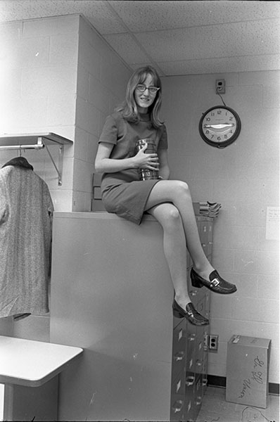 Young woman in a business skirt seated on a filing cabinet