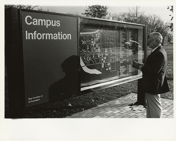 Man in a blazer looking at a map of campus