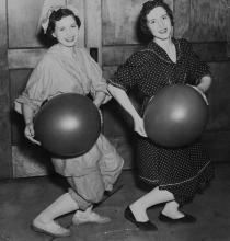 Two woman posing with large balloons